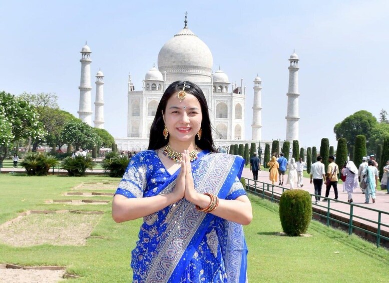 A person in traditional attire standing in front of the Taj Mahal. 2