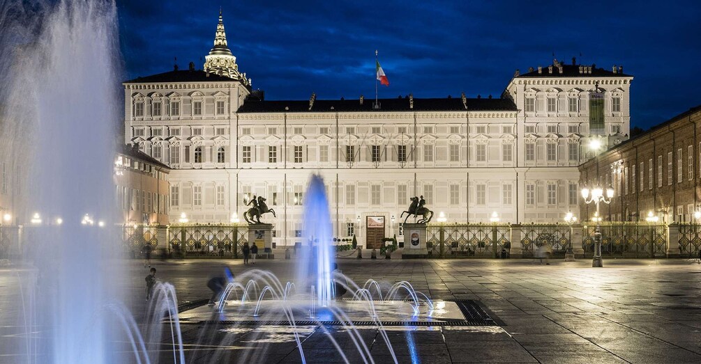 A large white building with a fountain in front. 1