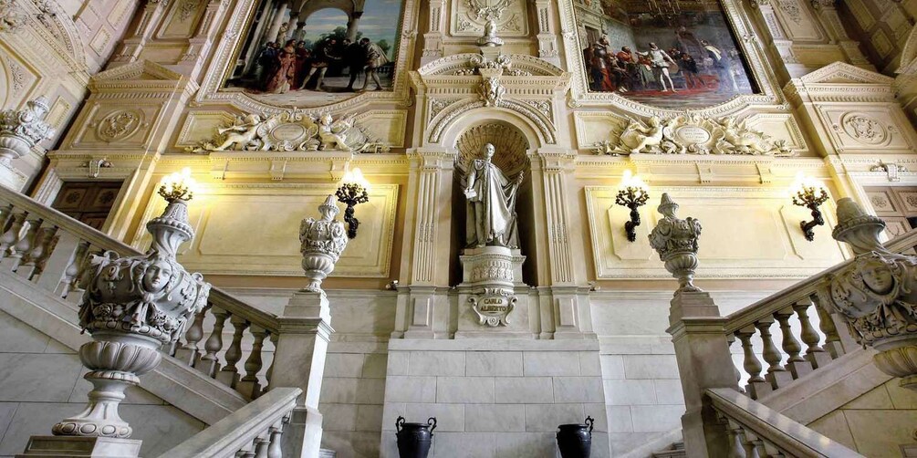 An ornate staircase with intricate carvings and statues, leading to a grand hall with a large painting and decorative moldings. 4
