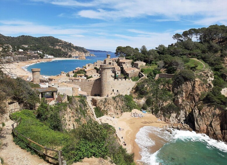 A coastal town with a historic castle, beach, and rocky cliffs. 3