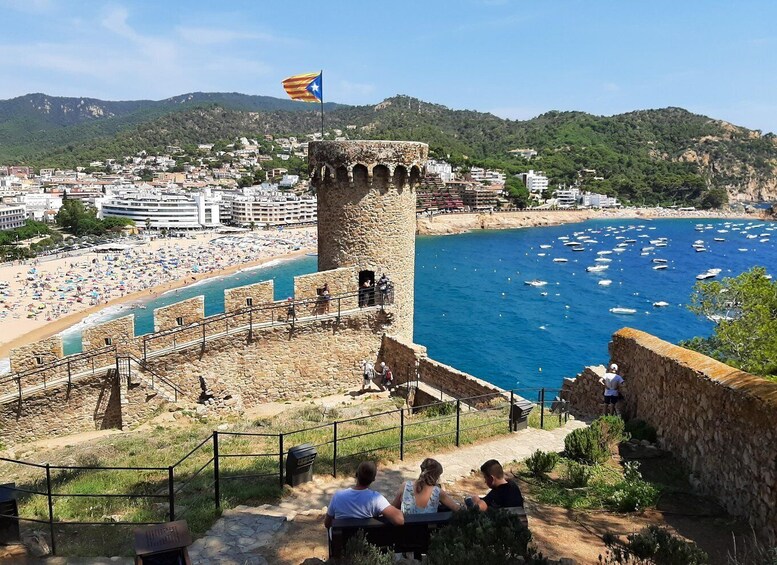 A coastal town with a historic tower, a beach, and boats in the water. 4