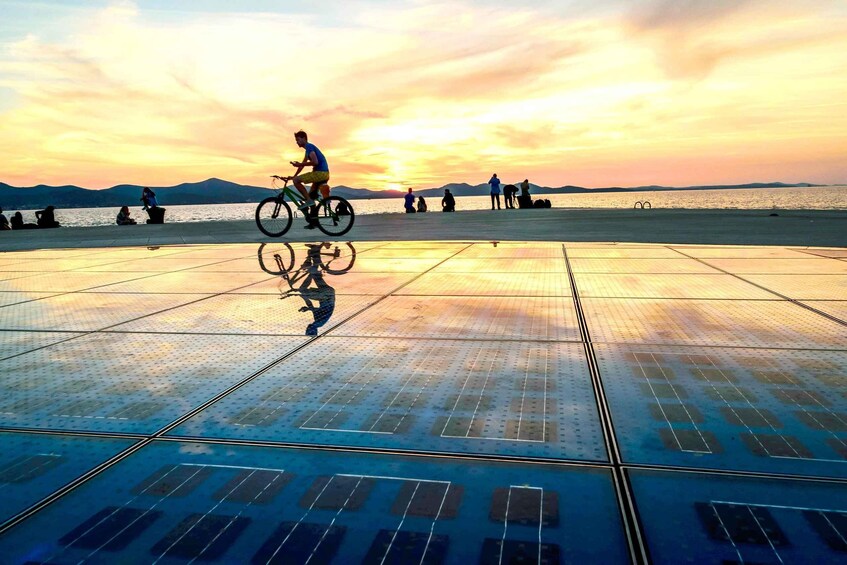 A person riding a bicycle on a reflective surface with a sunset in the background. 2