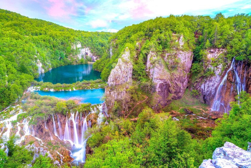 A lush valley with multiple waterfalls, a turquoise lake, and dense green forests. 5