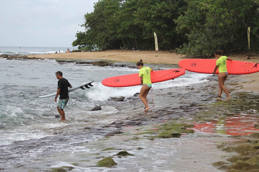 People carrying surfboards along a rocky shoreline. 4