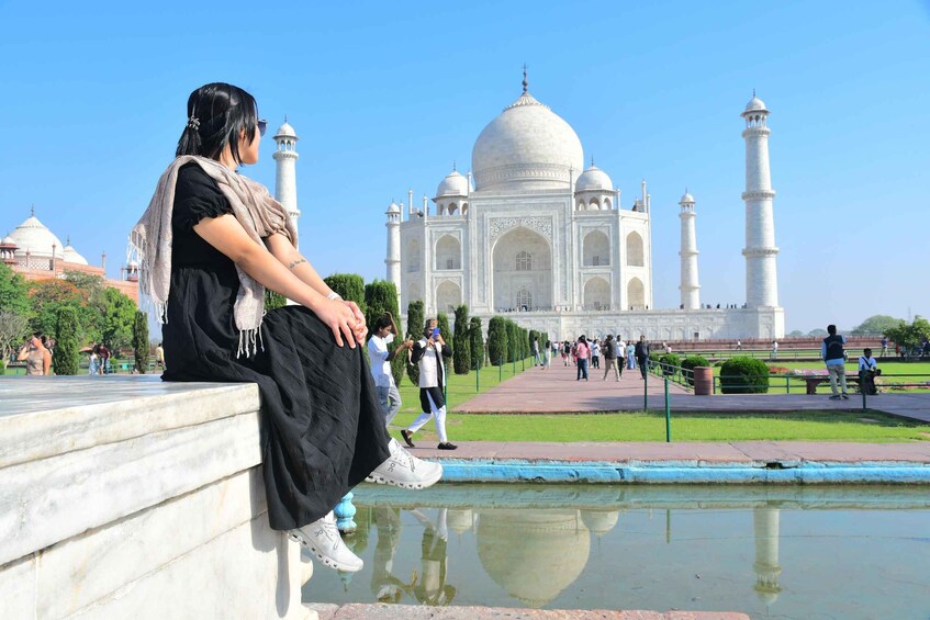 A person sitting on a marble ledge with the Taj Mahal in the background. 2