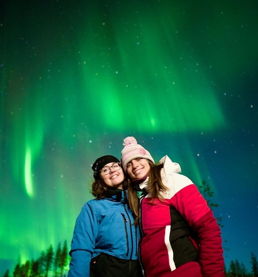 Two people standing under the aurora borealis. 2