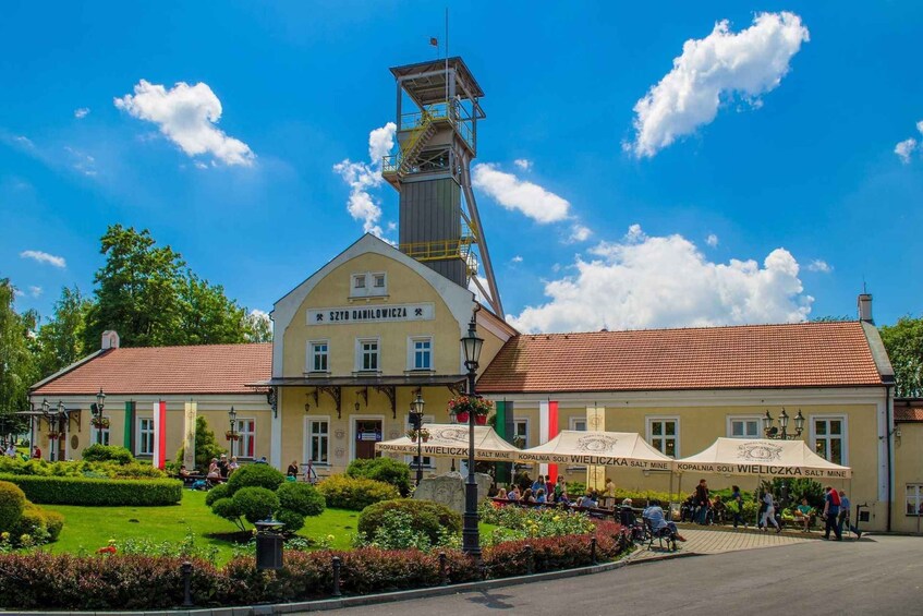 A building with a tower, a garden, and people sitting outside. 3
