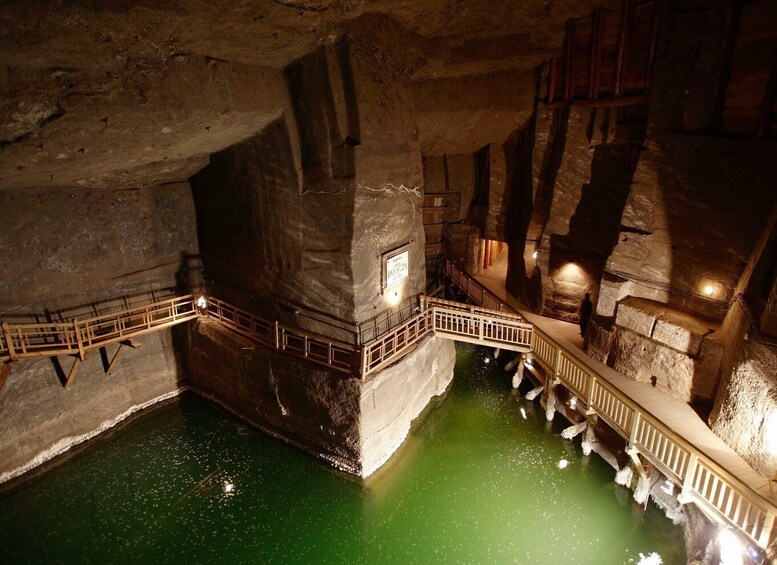 A cave with a wooden walkway over a green pool. 1