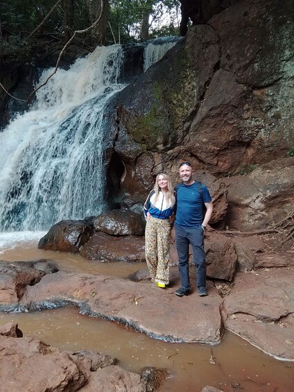 A waterfall with two people standing on rocks. 5