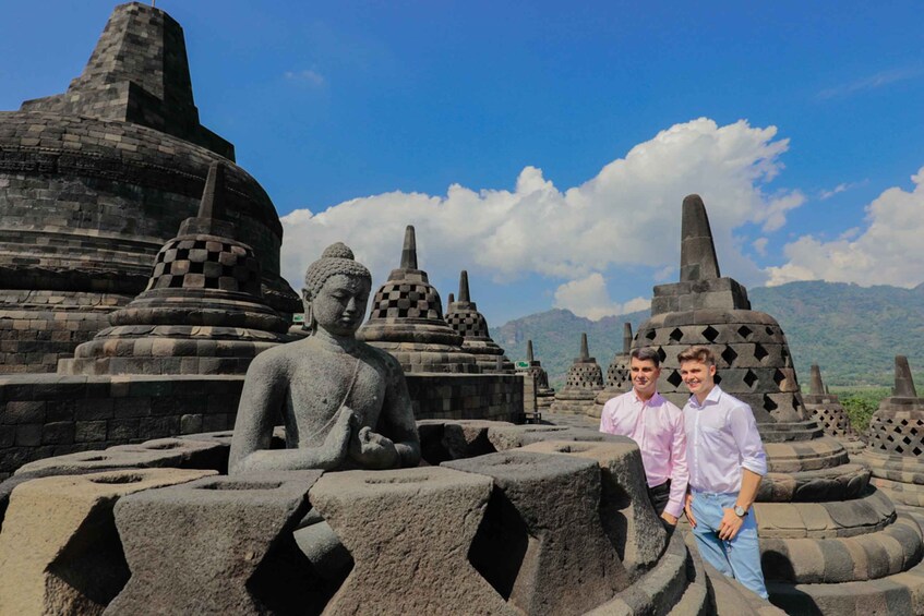 A large Buddha statue surrounded by ancient stone structures and mountains in the background. 1
