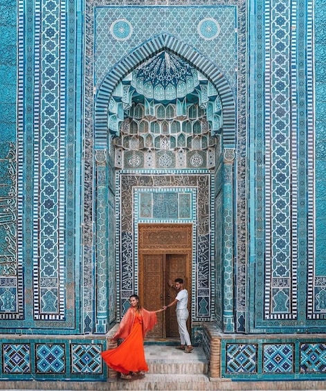 A man and a woman in traditional attire standing in front of a intricately designed doorway. 5