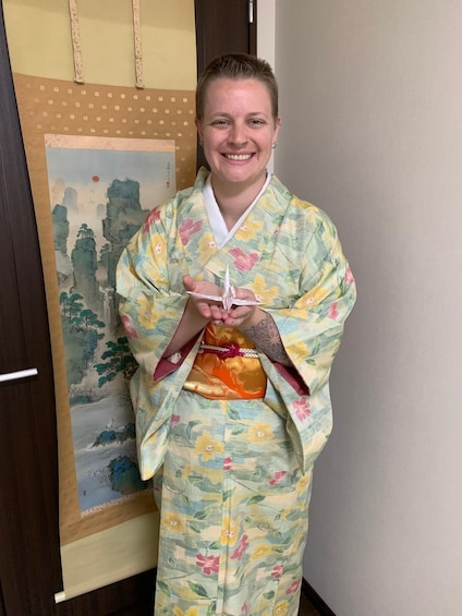 A person in a colorful kimono standing in front of a painting. 2