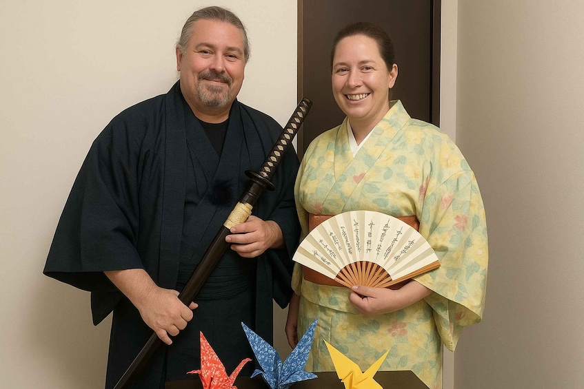Two people in traditional attire, one holding a fan and the other a sword. 1