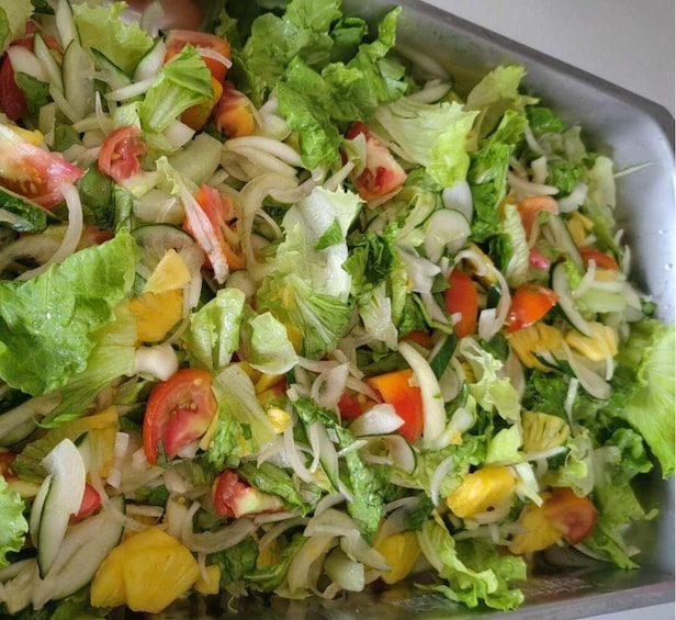 A tray of mixed salad with lettuce, tomatoes, onions, and pineapple. 4