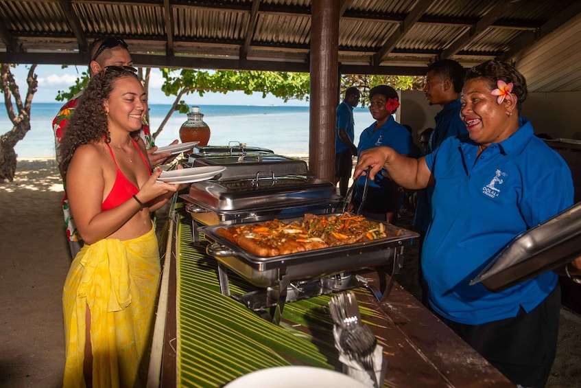 A buffet setup with food trays and a person serving food. 5