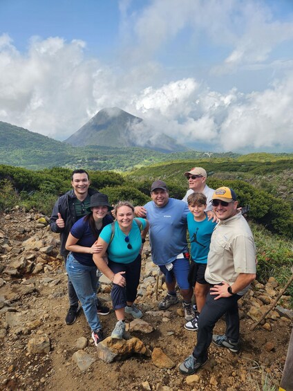 A group of people standing on a rocky terrain with a mountain in the background. 2
