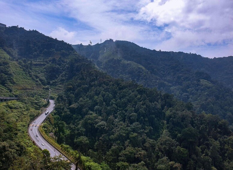 A winding road through a dense forested mountain range. 1