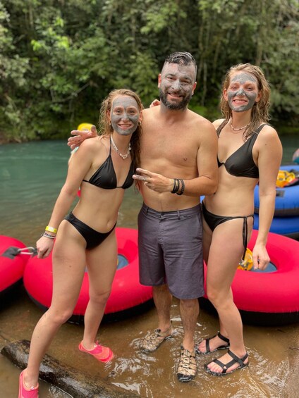 Three people in black swimwear standing in shallow water with a raft in the background. 5