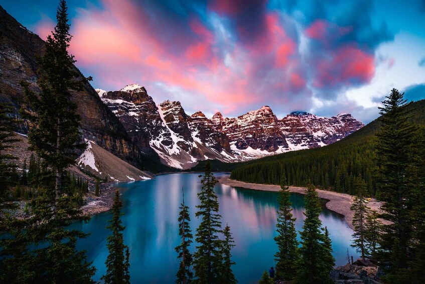 A mountain range with a turquoise lake surrounded by dense forests. 1