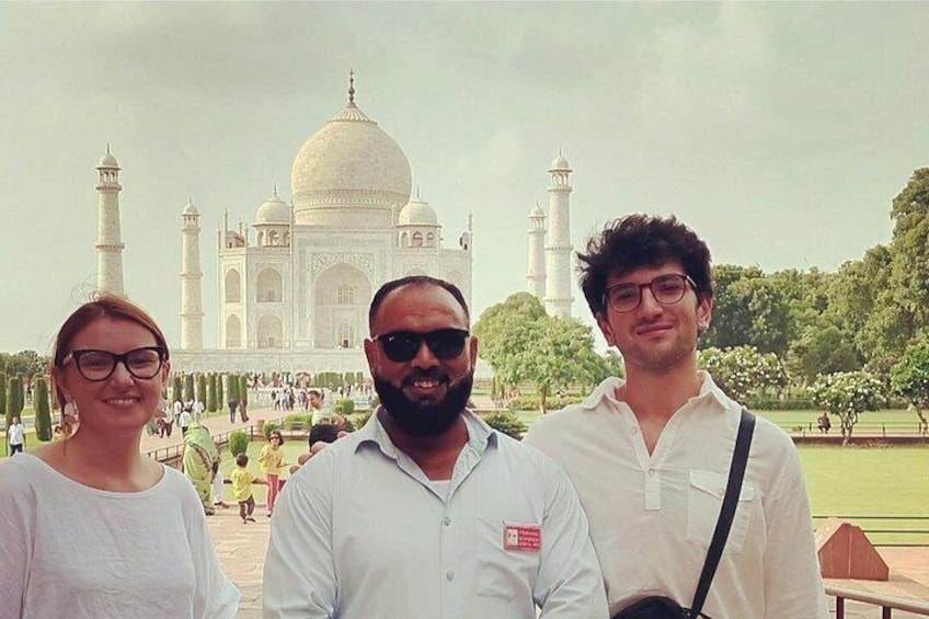 Drei Personen vor dem Taj Mahal, mit Kuppeln und Minaretten im Hintergrund. 3