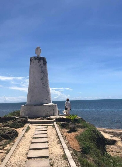 A lighthouse with a person walking towards it. 1