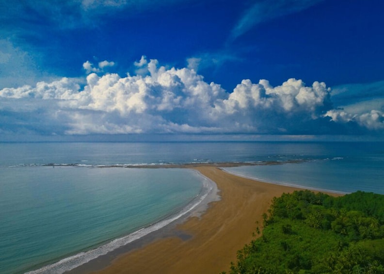 A beach with a curved shoreline, a clear sky, and scattered clouds. 2