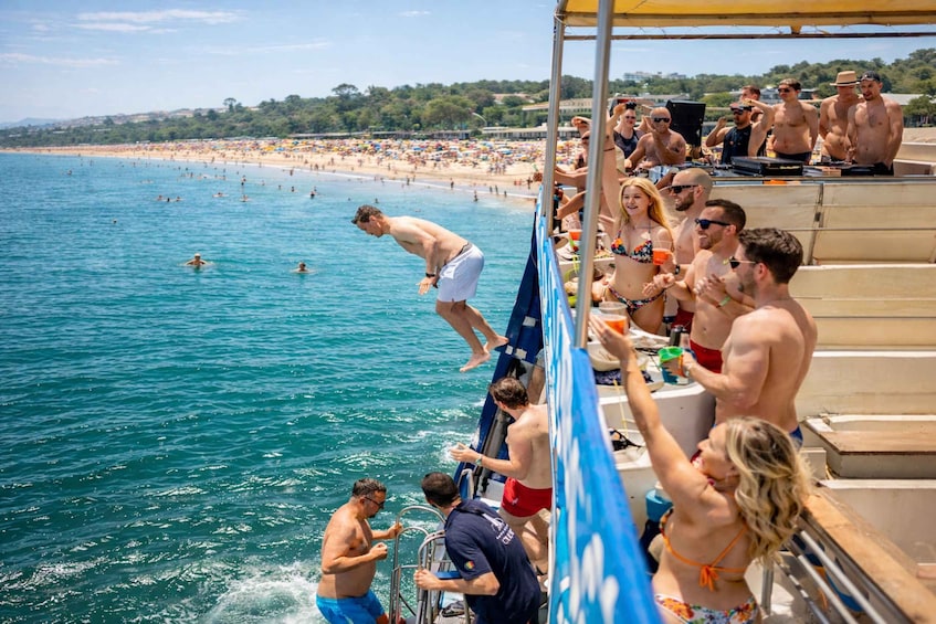 A man jumping off a boat into a crowded beach. 1