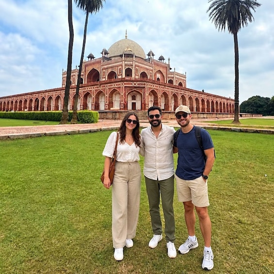 Three people standing in front of a large, historic building with a dome and arches. 1
