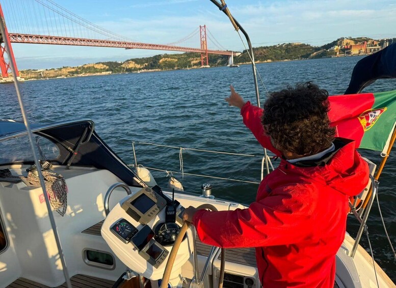 A child in a red jacket on a boat, pointing towards a red bridge in the distance. 4