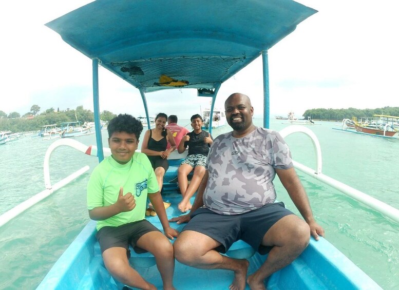 A group of people on a boat with a blue canopy, surrounded by calm water and other boats in the distance. 1