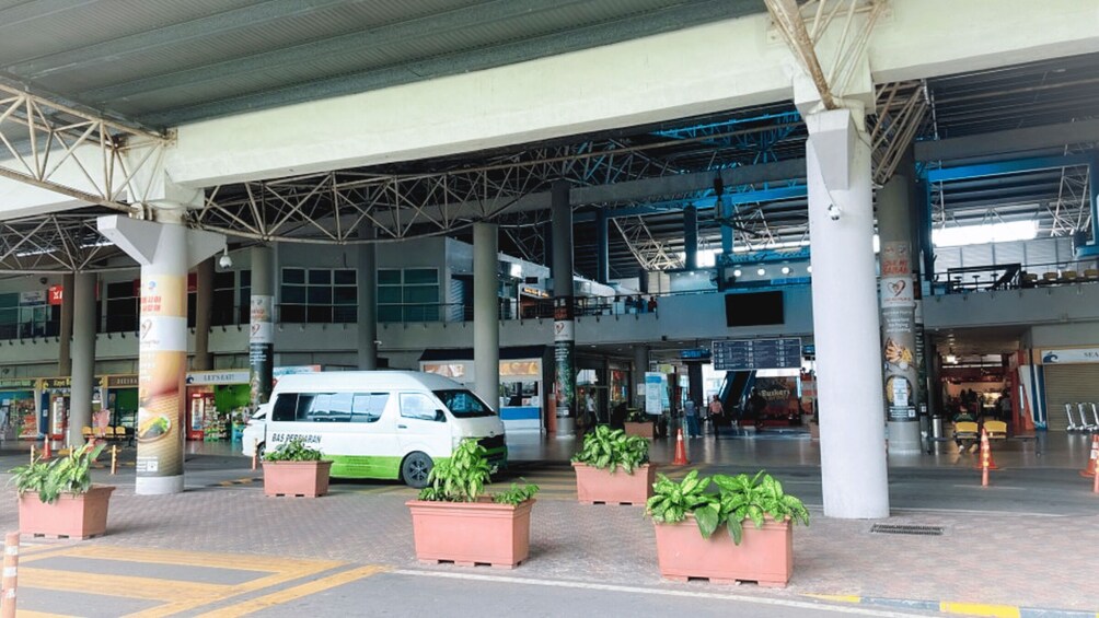 A white van parked at a toll booth with potted plants in the foreground. 2