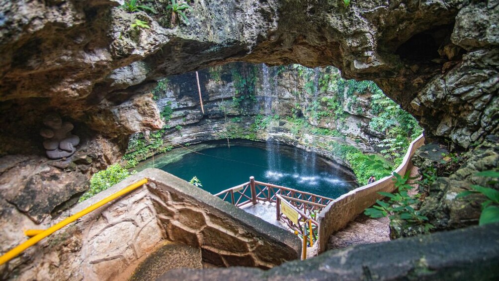 En naturlig grotta med en vattenpool, omgiven av klippväggar och grönska. 1