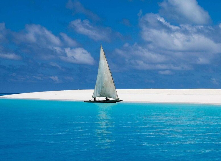 A sailboat on turquoise water with a white sandy beach and a clear sky. 2