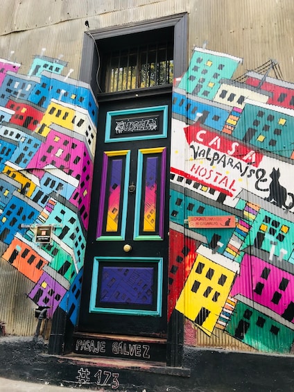 A colorful hostel door with a mural of buildings. 1