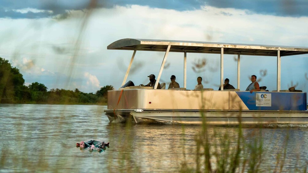 A boat with passengers on a calm river, surrounded by greenery. 5