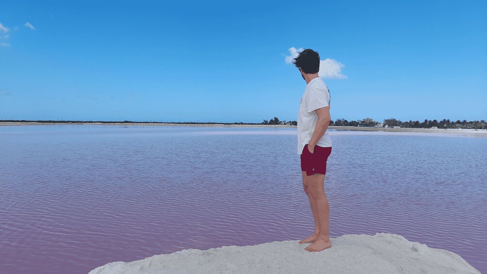 A person standing on a white sandbar in a body of water with a clear sky. 4