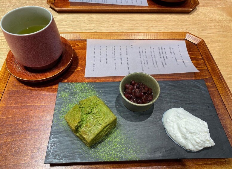 A meal with a green dessert, a bowl of red beans, and a cup of green tea on a wooden tray. 4