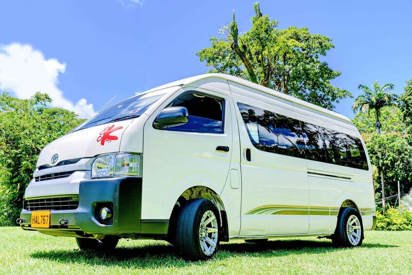 A white van parked on grass with trees in the background. 4