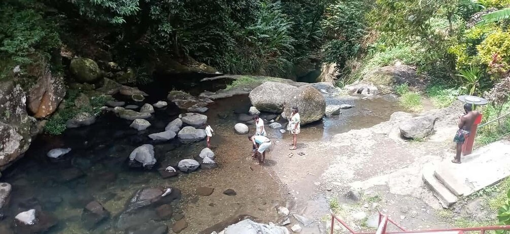 A rocky stream with people standing and sitting around it. 2
