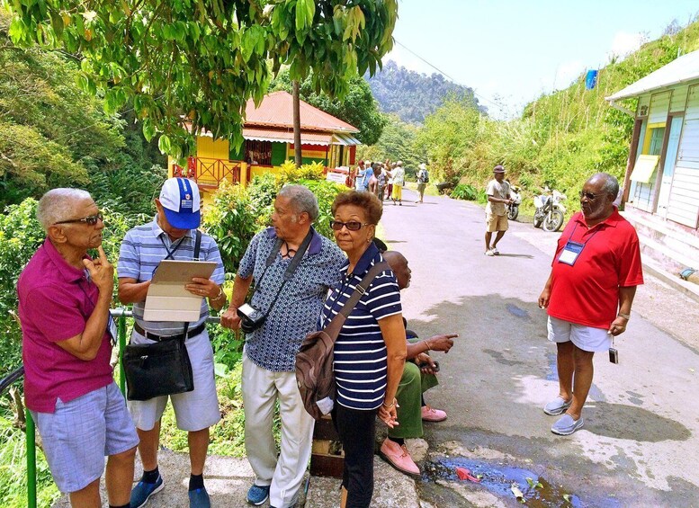 A group of people standing on a road with greenery and a building in the background. 3