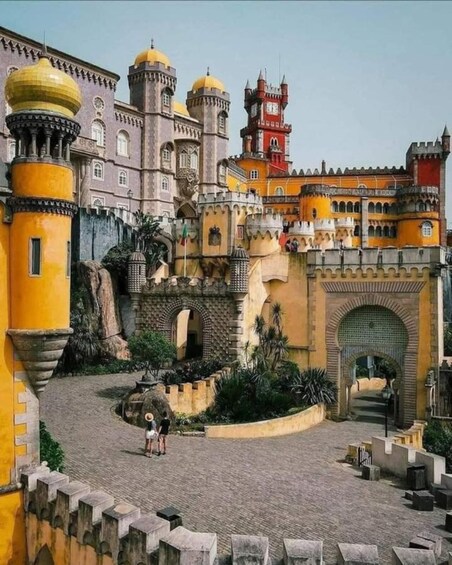 Un castello con mura gialle e arancioni, una torre centrale e un cortile con una fontana. 3