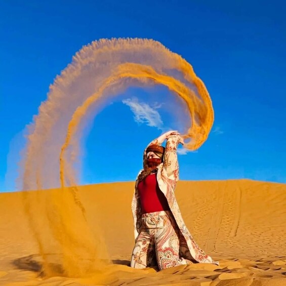A person in a desert with sand dunes and a clear sky. 2