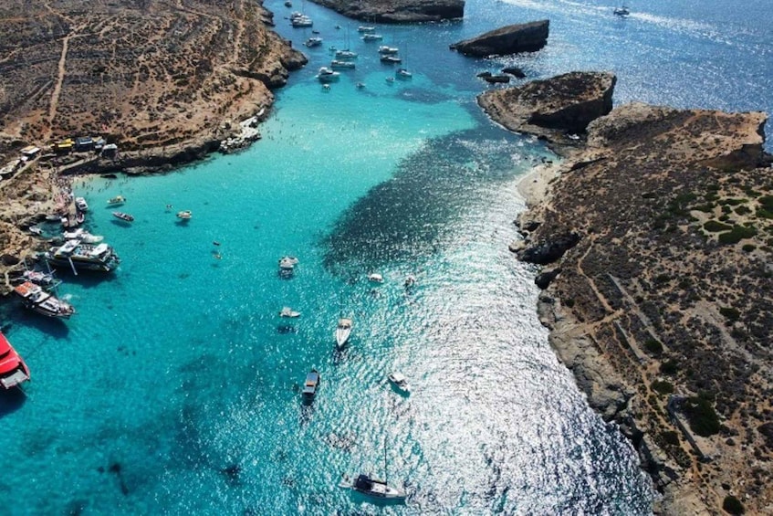 A coastal area with boats anchored near rocky shores and a clear blue sea. 1