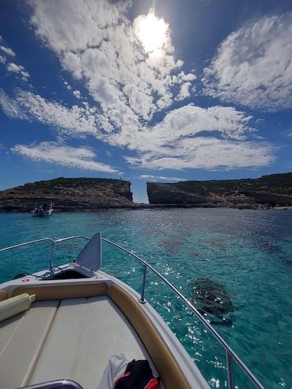 A boat on clear turquoise water with rocky cliffs in the background. 5