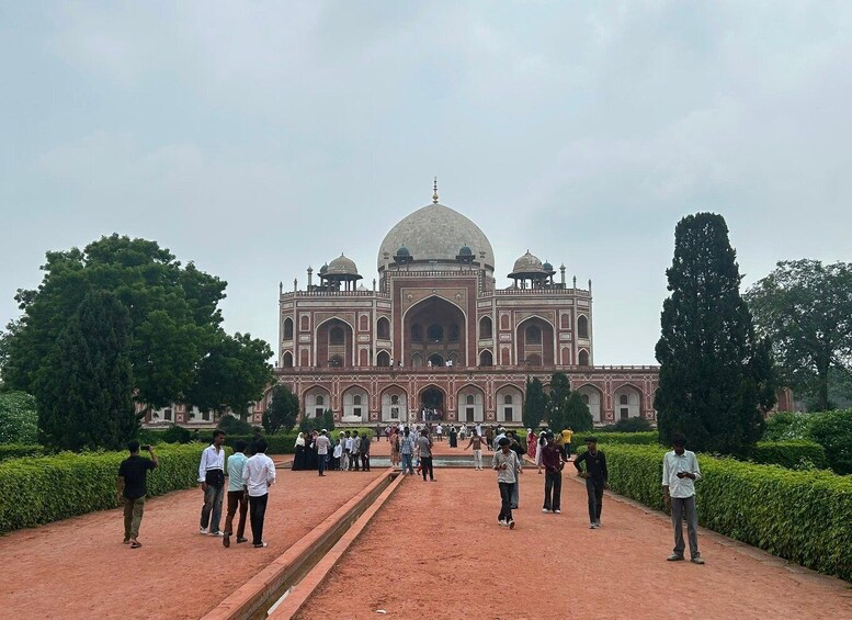 The Taj Mahal with a pathway leading to its entrance, surrounded by greenery and a crowd of people. 5