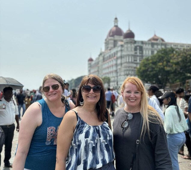 Three people standing in front of a large building with domed roofs. 1