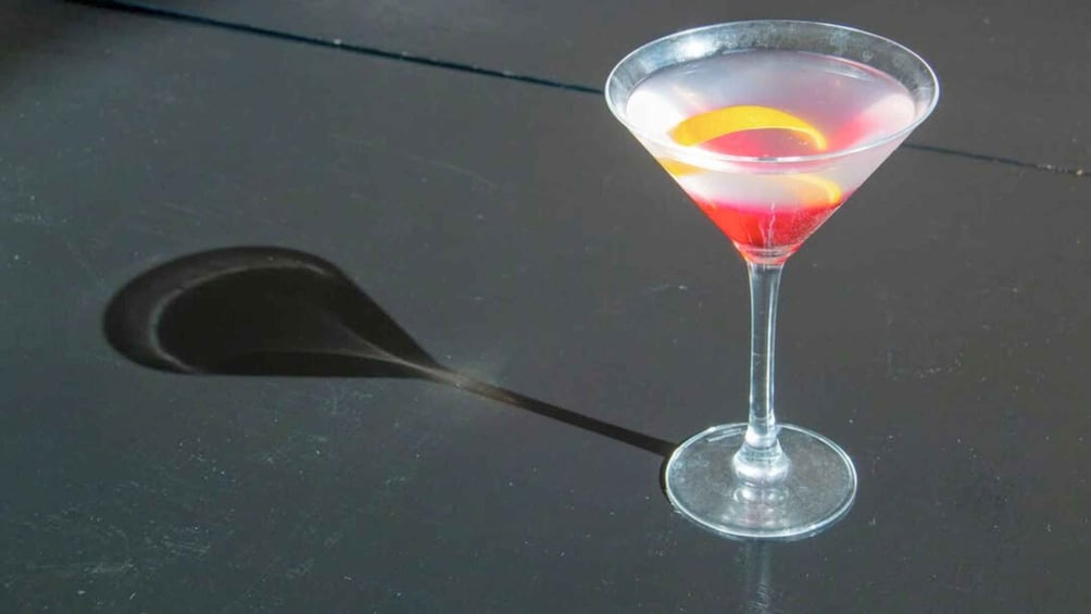 A martini glass with a lemon slice on a dark surface. 1
