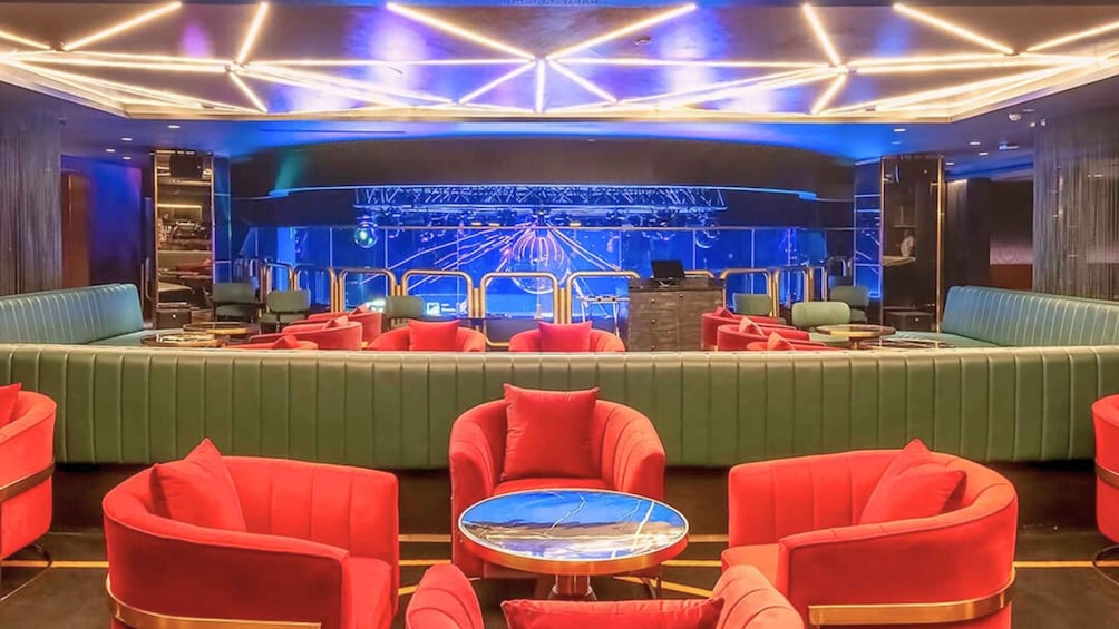 A modern lounge with green and red seating, a stage with blue lighting, and a futuristic design. 2