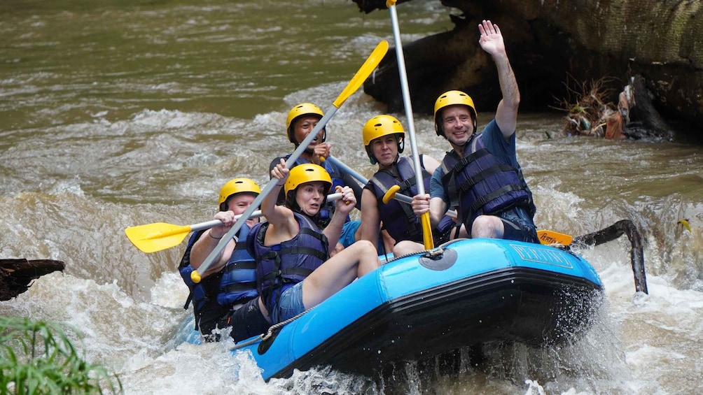 A group of people in a blue raft navigating a river with rapids. 1