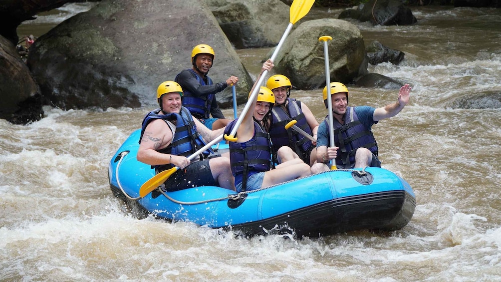 A group of people in a blue inflatable raft navigating a river with rapids. 5
